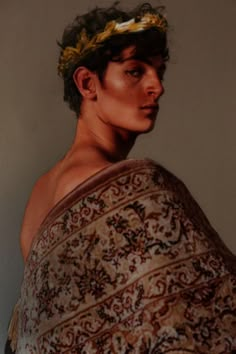 a young man wrapped in a towel with a flower on his head is staring at the camera