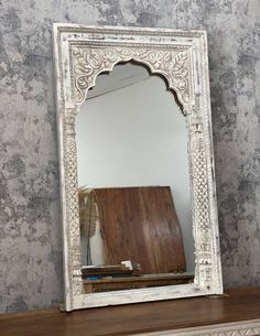 a mirror sitting on top of a dresser next to a wall