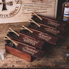 five wooden boxes with labels on them sitting on a table next to a bottle of alcohol