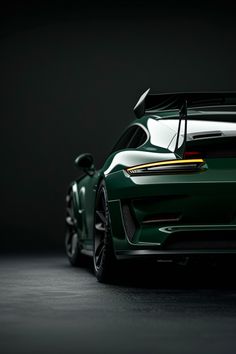 the rear end of a green sports car in a dark room with its hood open