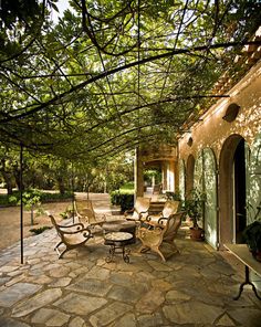 an outdoor patio with tables and chairs under a pergolated roof, surrounded by greenery