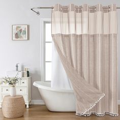 a bath tub sitting next to a shower curtain in a bathroom on top of a hard wood floor