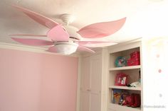 the ceiling fan is pink and white in this girls'room with bookshelves