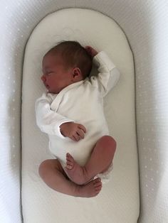 a baby laying on top of a white mattress