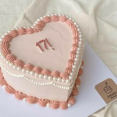 a heart - shaped cake with pearls and pink icing is on a white tablecloth