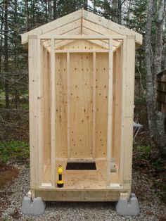 a small wooden outhouse in the woods