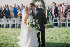 a bride and groom kissing in front of an outdoor wedding ceremony with people watching them