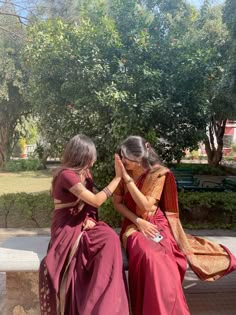 two women are sitting on a bench and touching hands