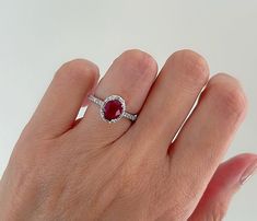 a woman's hand with a ring on it and a red stone in the middle