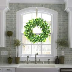 a kitchen sink with a wreath hanging from the window