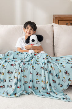 a young boy laying on top of a couch holding a stuffed animal in his arms