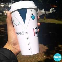 a person holding up a coffee cup with a doctor's coat on the side