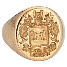 Finely detailed vintage Art Deco era family crest signet ring (circa 1920s to 1930s) crafted in 14 karat yellow gold. The signet ring weighs a hefty 18.7 grams. The signet mount features a castle framed with wreaths to the sides. The base of the signet mount reads in Latin the phrase 'suaviter sedfortiter' or 'Gently buy Bravely'. 'Mossburg' appears beneath and we believe this a reference to a family name. The low rise ring (4mm - 0.15 inches) sits comfortably on the finger. The ring is in very good condition. We have not cleaned it in order to preserve the patina and collector value. Particulars: Weight: 18.7 grams Stones: N/A. Size & Measurements: The ring is a size 9 3/4 (sizable). The mount measures 20mm in length (0.78 inches) and 18.5mm wide (0.72 inches) rising 3mm from the finger. Signet Rings Women Vintage, Family Crest Rings, Art Deco Jewelry Vintage, Signet Rings Women, Family Rings, Gold Signet Ring, Yellow Gold Jewelry, Art Deco Era, Family Crest