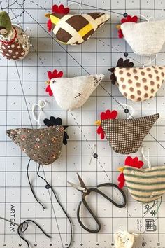 several different types of bird ornaments on a cutting board with scissors and thread spools