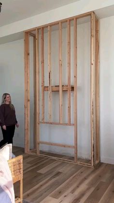 a woman is standing in the middle of a room with wood framing on the walls