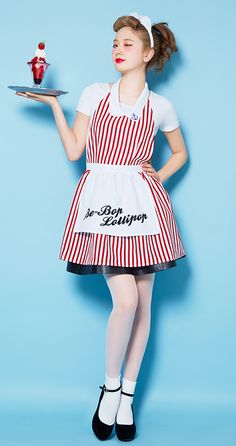 a woman in an apron holding a plate with a cupcake on it