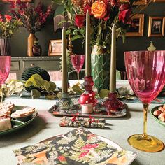 a table topped with plates and vases filled with flowers