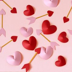 valentine's day decorations made out of paper hearts and arrows on a pink background