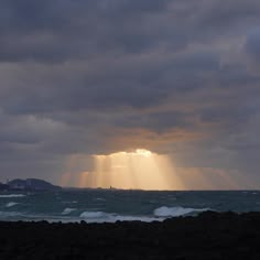 the sun is shining through clouds over the ocean