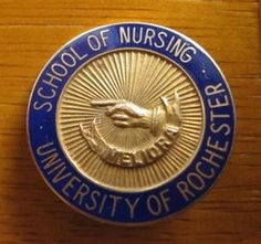 a blue and gold school of nursing emblem on a wooden surface with the words school of nursing written below it