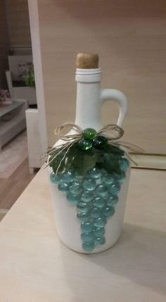 a white vase with green glass beads and a corkscrew on the top is sitting on a table