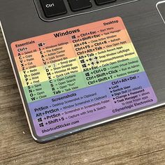 a laptop computer sitting on top of a table with a rainbow sticker on it