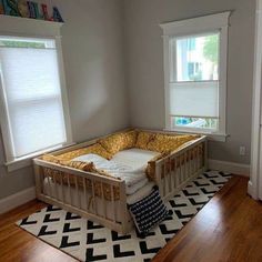 a baby crib in the corner of a room with two windows and a rug on the floor