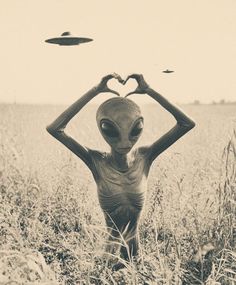 an alien standing in the middle of a field holding his hands up to his head