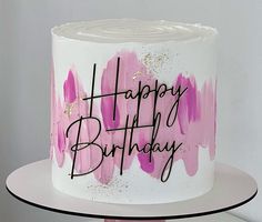 a white and pink birthday cake with black writing on it