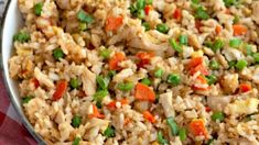 rice with peas and carrots in a white bowl on a red checkered cloth