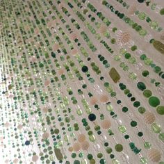 green and white sequins are arranged on a tablecloth that looks like it has been made out of glass beads