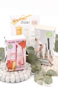 the contents of an assortment of beauty products displayed on a white surface with green leaves