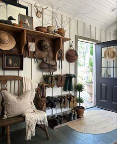 a room with many hats and shoes hanging on the wall next to a bench in front of a door