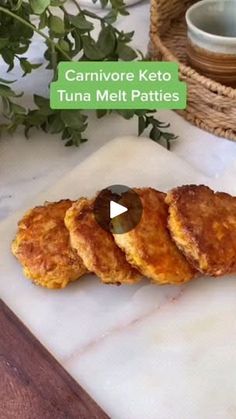 three fried food items on a cutting board next to a basket and bowl with green leaves