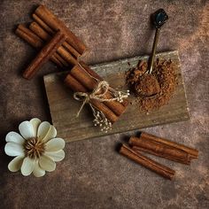 cinnamon sticks and spices on a cutting board next to a flower with a spoon in it