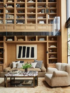 a living room filled with furniture and bookshelves next to a large glass window