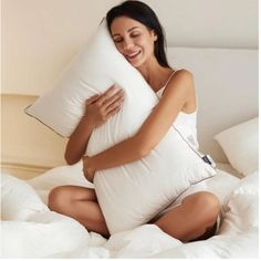 a woman sitting on a bed holding a pillow