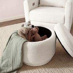 a teddy bear sitting in a white chair with a blanket on the floor next to it