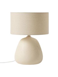 a white table lamp with a beige shade on the base and a cord attached to it