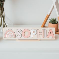 a wooden sign with the word sophia written on it next to some succulents