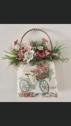 a white bag with flowers in it hanging on a wall next to a planter