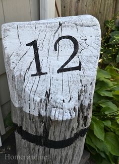 a wooden sign with the number twelve painted on it's side in front of a house