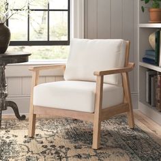 a white chair sitting on top of a rug next to a table with a potted plant