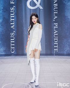 a woman is walking down the runway in thigh high boots and an off - white dress