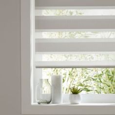 a white window with blinds and vases on the windowsill in front of it