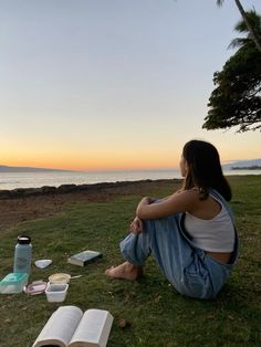 a woman sitting on the grass next to an open book