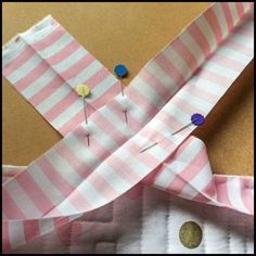 some pink and white striped fabric with buttons on it's side, next to a pair of scissors