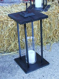 two candles are sitting on a table with hay in the background