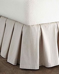 the bed skirt is made from linen and has pleated edges