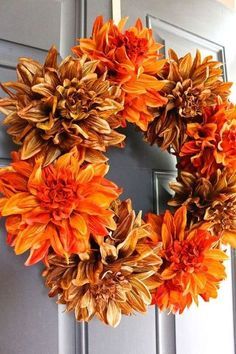 a wreath with orange flowers hanging from it's side on the front door,